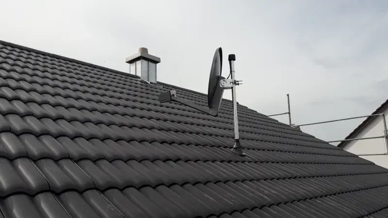 Satellitenschüssel auf einem dunklen Ziegeldach nach der Installation
