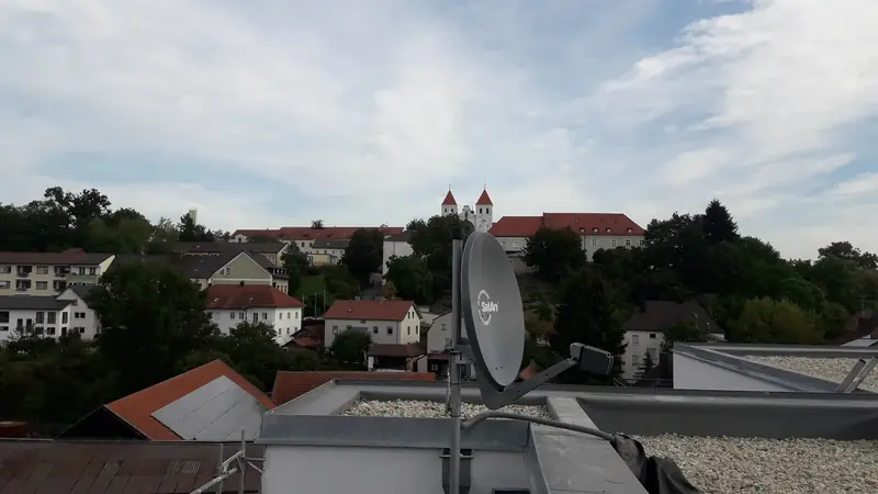 Satellitenschüssel auf einem Flachdach mit Blick über den Ort