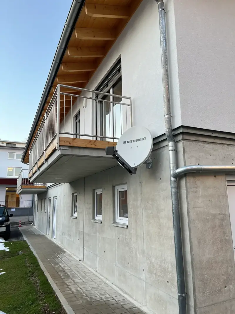 Satellitenschüssel am Balkon eines Mehrfamilienhauses