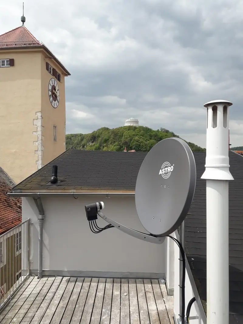 Satellitenschüssel auf einer Dachterrasse vor einem Turm