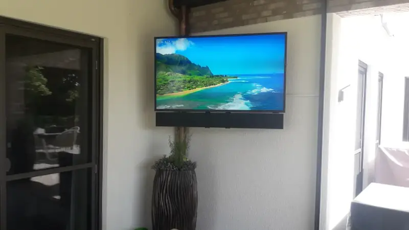 Wandmontierter Fernseher in einem hellen Raum mit großer Glastür – Referenz von Fernseh Wild