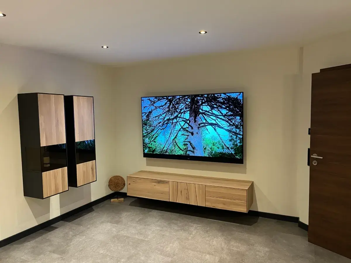 Wandmontierter Fernseher über einem Holz-Sideboard in einem neuen Wohnraum