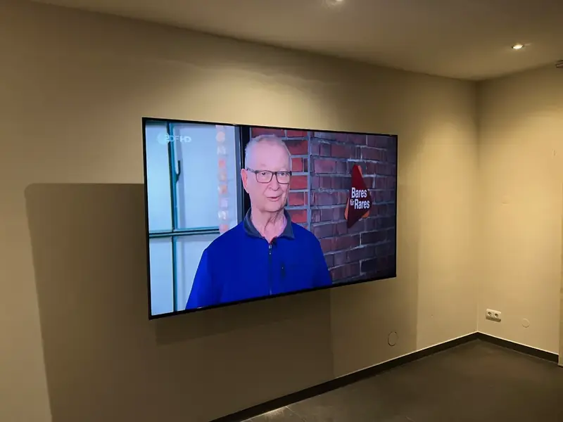 Großer Fernseher an der Wand eines Wohnraums nach der Montage