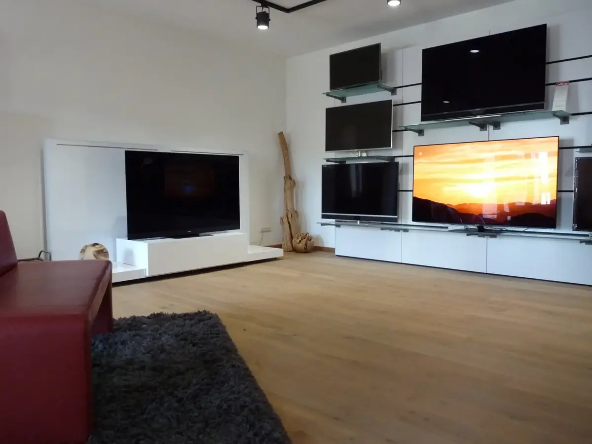 Fernseher-Ausstellung an einer weißen Präsentationswand im Showroom von Fernseh Wild