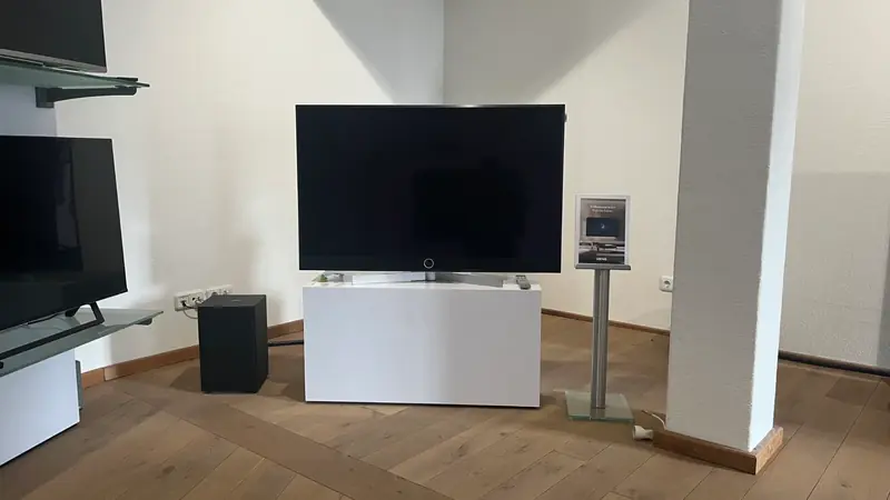 Fernseher auf weißem Lowboard neben einer Säule im Showroom