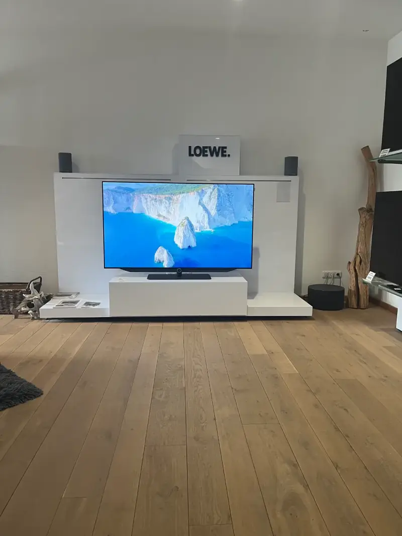 LOEWE-Fernseher auf einem weißen Lowboard im Showroom von Fernseh Wild
