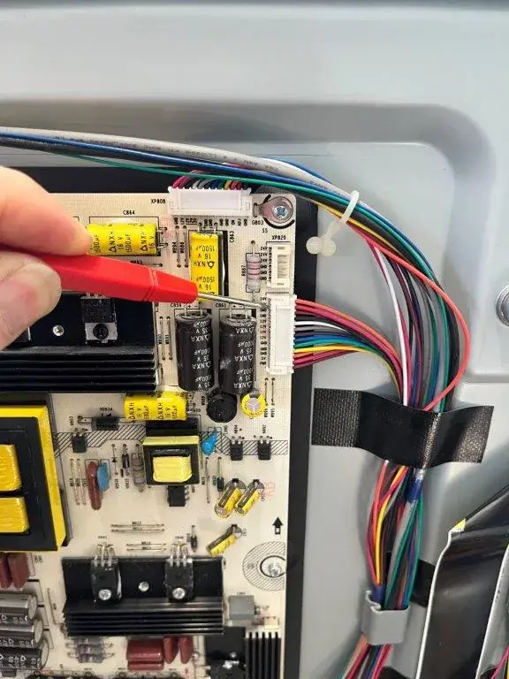 Techniker von Fernseh Wild prüft die Platine eines geöffneten Fernsehers bei der Reparatur